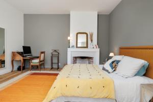 1 dormitorio con cama, chimenea y escritorio en L'escapade, en Carignan