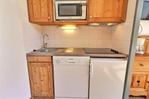 a small kitchen with a white refrigerator and a microwave at Le Grand Bois in Courchevel