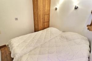 um quarto com uma cama branca e uma porta de madeira em Le Grand Bois em Courchevel