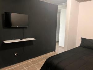 a bedroom with a black wall with a tv on the wall at PFKR in San Juan