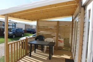 uma pérgola de madeira com uma mesa num deque em Mer et Soleil a la cote d'opale em Le Portel