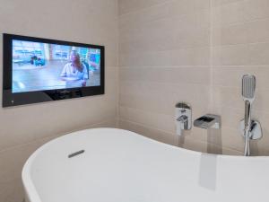 uma casa de banho com banheira e uma televisão na parede em Pass the Keys Contemporary Apartment with Secure Parking em Shrewsbury