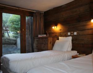 1 dormitorio con 2 camas y ventana en Alpina Lodge Chalet By Valdiski en Val dʼIsère