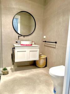 La salle de bains est pourvue d'un lavabo blanc et d'un miroir. dans l'établissement Mountain Cottage in Dandenong Ranges, à Mont Dandenong