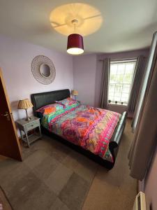 a bedroom with a bed with a colorful comforter and a window at Old Dairy in Tain