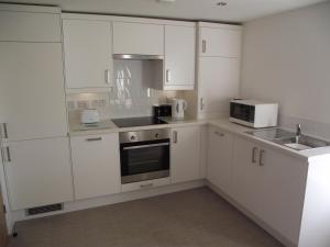 a kitchen with white cabinets and a sink and a microwave at 6B Church St. Dingwall Apartment in Dingwall