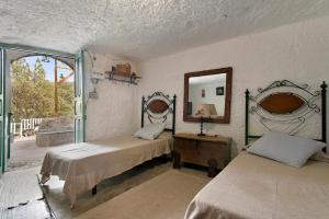 1 dormitorio con 2 camas y espejo en la pared en La Cuevita de Hilario en Artenara