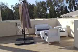 a patio with an umbrella and chairs and a table at סוויטה נוף היובלים in Qasrîne