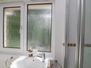 a bathroom with a sink and two windows and a shower at 3 Bonaventure Close in Salcombe
