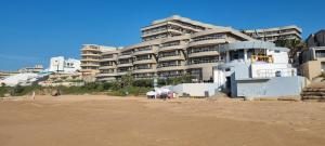 a building on the beach next to a sandy beach at 305 Ballito Manor Gardens, Ballito - With Generator in Ballito