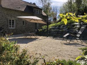 a patio with an umbrella and chairs and a building at Le Pralat in Pont-et-Massène
