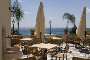 an outdoor patio with tables and white umbrellas at Palazzo Reginella in Bovalino Marina