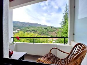 a chair sitting on a balcony looking out a window at Tílias House in Covilhã
