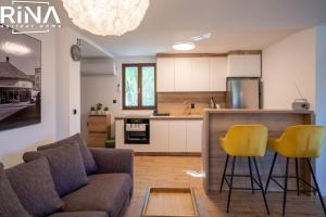 een woonkamer met een bank en twee gele barkrukken bij Kuća za odmor Rina in Pakrac