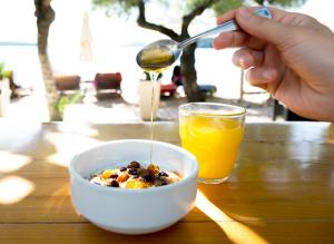 a person is pouring orange juice into a bowl of cereal at Armeno beach hotel in Nydri