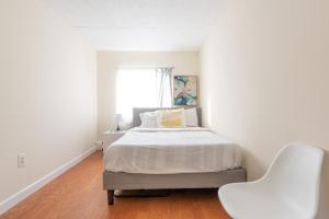 a white bedroom with a bed and a white chair at Stunning 2 BR in Manhattan in New York