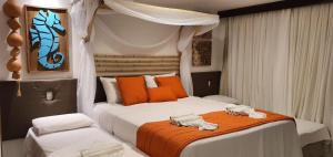 een slaapkamer met 2 bedden met oranje en wit bij Porto Praia Resort Marulhos in Porto De Galinhas