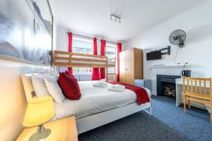 a bedroom with a bed with red curtains and a fireplace at The Buross - Aldgate in London