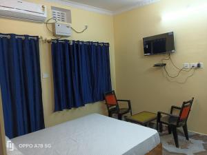 een kamer met een bed en twee stoelen en een televisie bij TITILI PLAZA in Puri