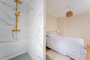 una camera da letto con pareti in marmo bianco e un letto di La Perle de Lens - Belle maison avec grande terrasse a Lens