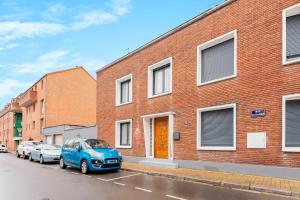 una macchina blu parcheggiata di fronte a un edificio di mattoni di La Perle de Lens - Belle maison avec grande terrasse a Lens