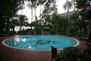 a large swimming pool in a resort with palm trees at Mui Ne Resort in Mui Ne