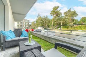 a patio with chairs and a table with flowers on a balcony at Apartament Doris 3- Studio z wanną in Pobierowo