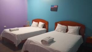 duas camas com lençóis brancos e uma toalha em HOTEL RAYMONDI em Pucallpa