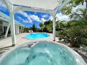 uma banheira de hidromassagem num quintal com uma pérgola em Villa Monica, maison idéale avec enfants em Saint-François