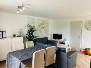 een eetkamer met een tafel en een bank en een tv bij Vakantiewoning Ter Streep in Middelkerke