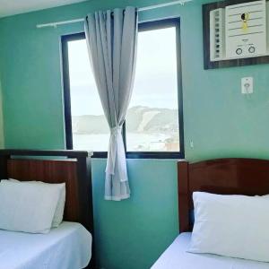 a blue room with two beds and a window at Conforto e melhor vista - 100 metros da praia in Natal