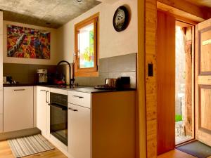 a kitchen with white cabinets and a clock on the wall at LA CÀ NOVA. South Switzerland cozy gate away. in Osco