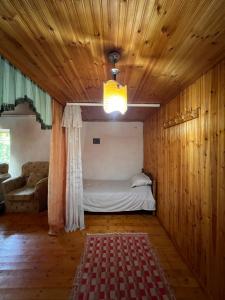 een slaapkamer met een bed in een kamer met houten wanden bij Goni Guest House in Tepelenë