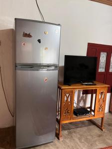 a refrigerator next to a table with a television at Goni Guest House in Tepelenë