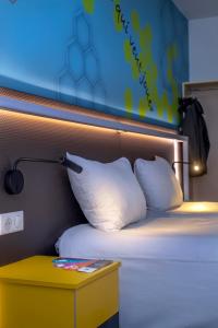 1 cama con 2 almohadas y mesita de noche junto a ella en ibis Styles Strasbourg Stade de la Meinau, en Estrasburgo