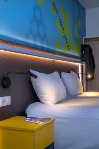 a bed with two pillows and a night stand next to it at ibis Styles Strasbourg Stade de la Meinau in Strasbourg