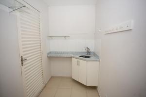 a small white kitchen with a sink and a door at Ribeiro Flat in Araxá