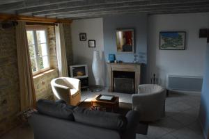 a living room with a couch and chairs and a fireplace at Les Chaufourniers/L'Etable in Crouay