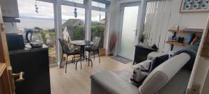 - un salon avec un canapé et une table avec des chaises dans l'établissement KINGHORN - Private room, ensuite & sunroom with Fab views, à Kinghorn