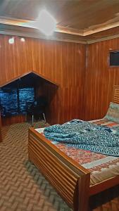 a bed in a room with wood paneled walls at Northern Huts And Riverview Restaurant in Bālākot