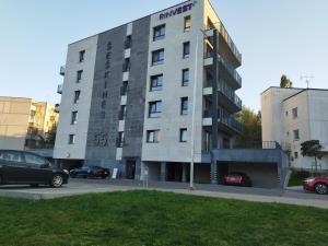 a building with cars parked in a parking lot at Cozy Apartment Vilnius in Vilnius