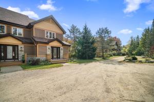 a house with a dirt road in front of it at Townhouse On The Golf W Pool Access -aiglon 1666 in Mont-Tremblant