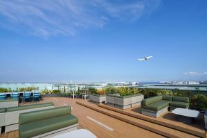 - un balcon avec des canapés et des chaises dans un bâtiment dans l'établissement Hotel Metropolitan Tokyo Haneda - 2023-10-17 Grand Opening, à Tokyo