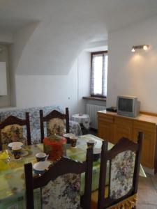ein Esszimmer mit einem Tisch, Stühlen und einem TV in der Unterkunft Apartments Gravedona Panoramic in Gravedona