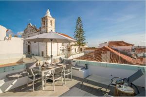 a patio with a table and an umbrella on a roof at Casa Machado in Lagos