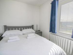 a bedroom with a white bed with two pillows and a window at Alauna View in Maryport