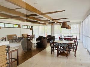 un comedor con mesas, sillas y ventanas en Apartamento Rio Marina Resort en Mangaratiba