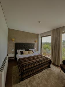 a bedroom with a large bed and a large window at Quinta de VillaSete in Alpendurada