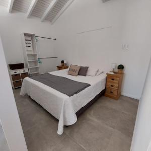 ein weißes Schlafzimmer mit einem Bett und einer Holzkommode in der Unterkunft Morning Star Aruba in Oranjestad