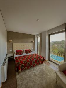 a bedroom with a large bed and a large window at Quinta de VillaSete in Alpendurada